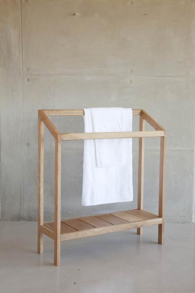 This is a double towel rail with a shelf, and a white towel draped over it. 