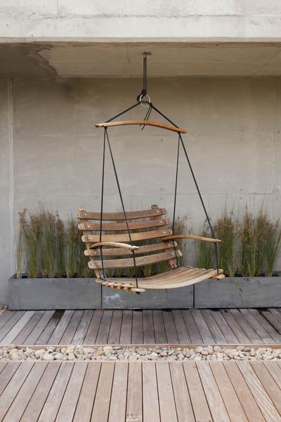 A wine barrel, patio swing chair, made from reclaimed oak, suspended by black yachting rope.